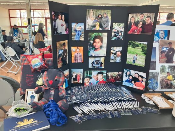 A posterboard with many photos of Angelo Quinto and merch.